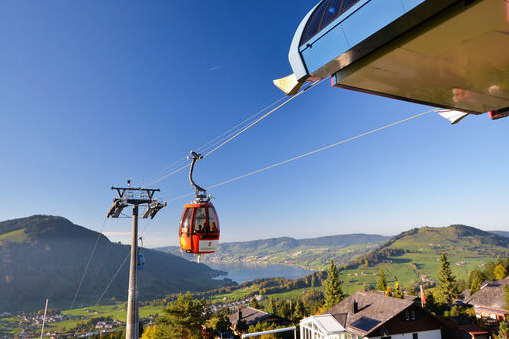 Ausblick von der Bergstation Richtung Ägerisee und die Berge. In der mitte des bildes ist eine rote Gondel