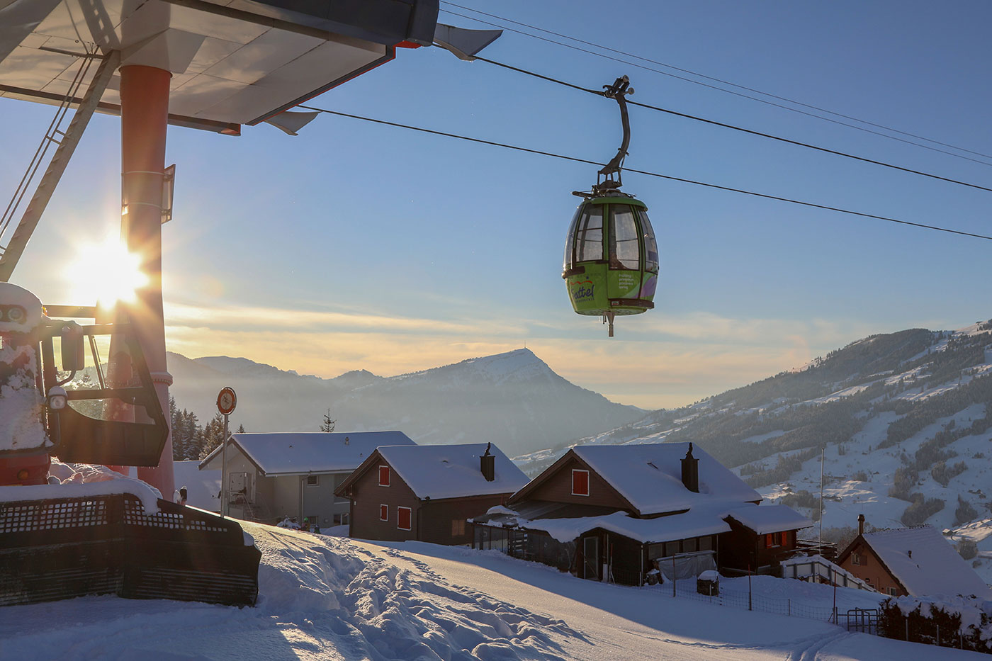 Winterbild von der Bergstation und einer einfahrender grünen Gondel. Im Hintergrund scheint die Sonne und man kann die Rigi sehen