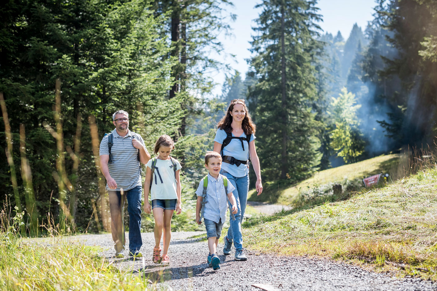 Eine Familie am wandern. Im Hintergrund ist ein Wald.