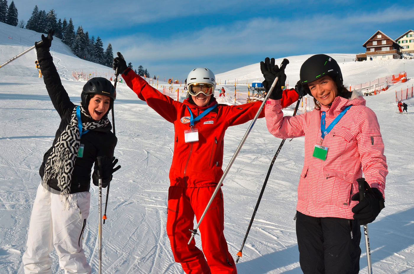 Skilehrer in Rot mit zwei Erwachsenen Skischülern. 