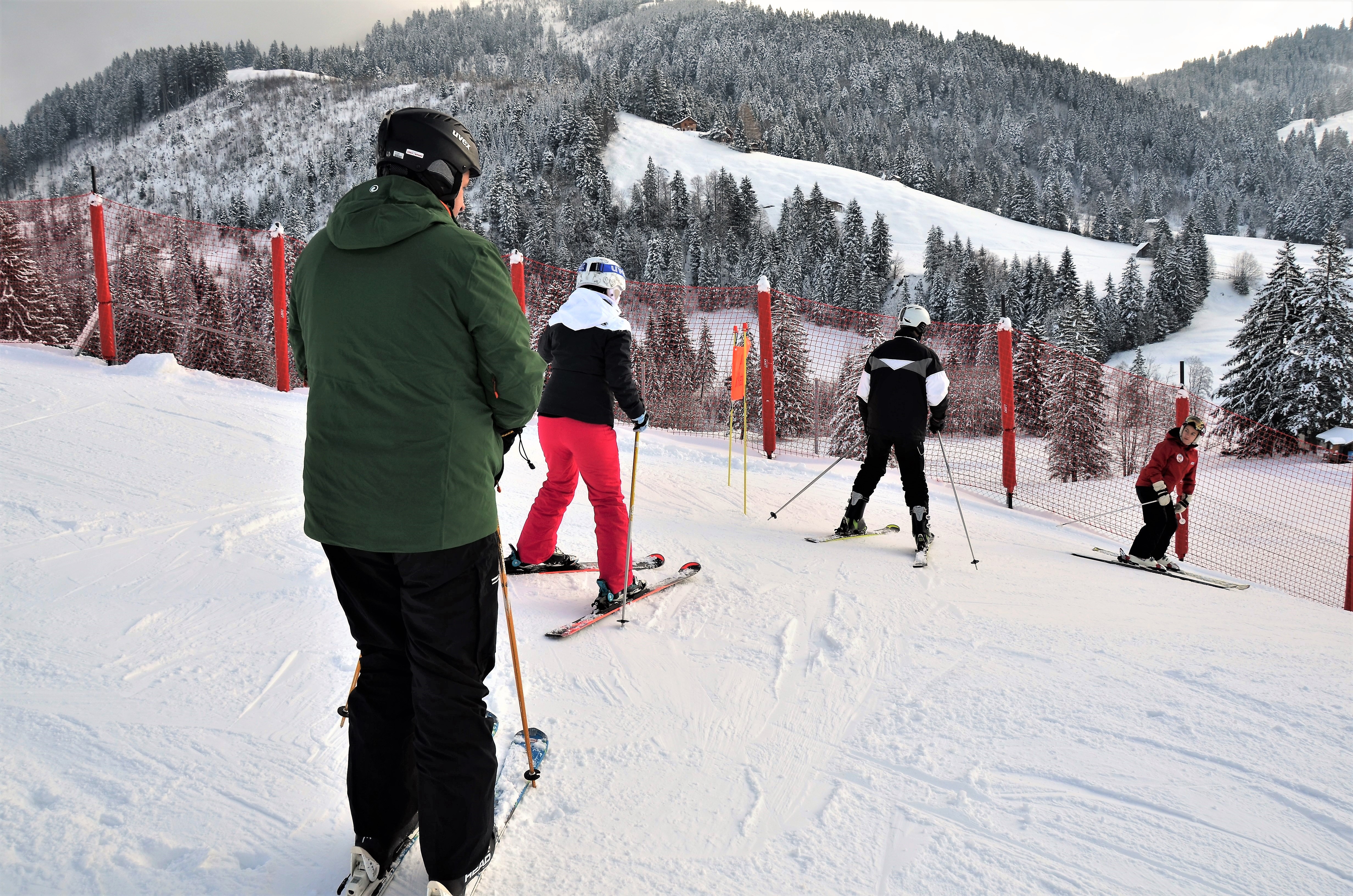 Drei erwachsene Skischüler die dem Skilehrer hinterher fahren. 