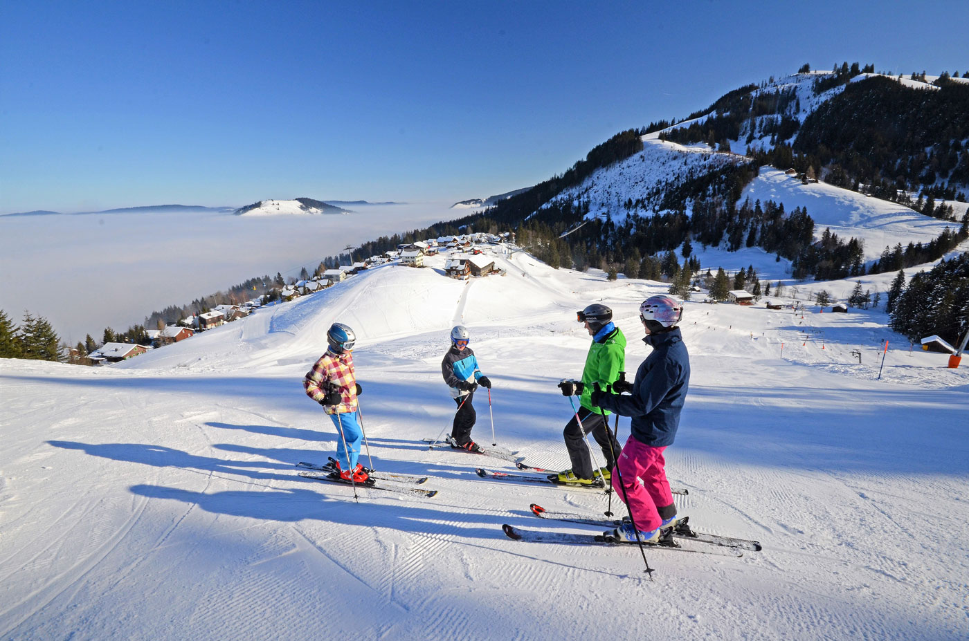 Vier Skifahrer am Start vom Hang mit blick auf das Nebelmeer. 