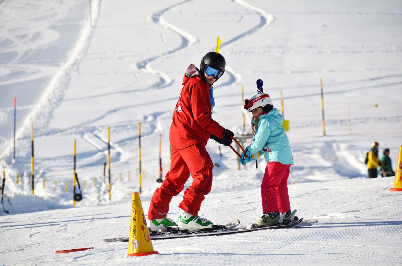 Skilehrer in rot mit Kind am Übung machen im Kinderland. 